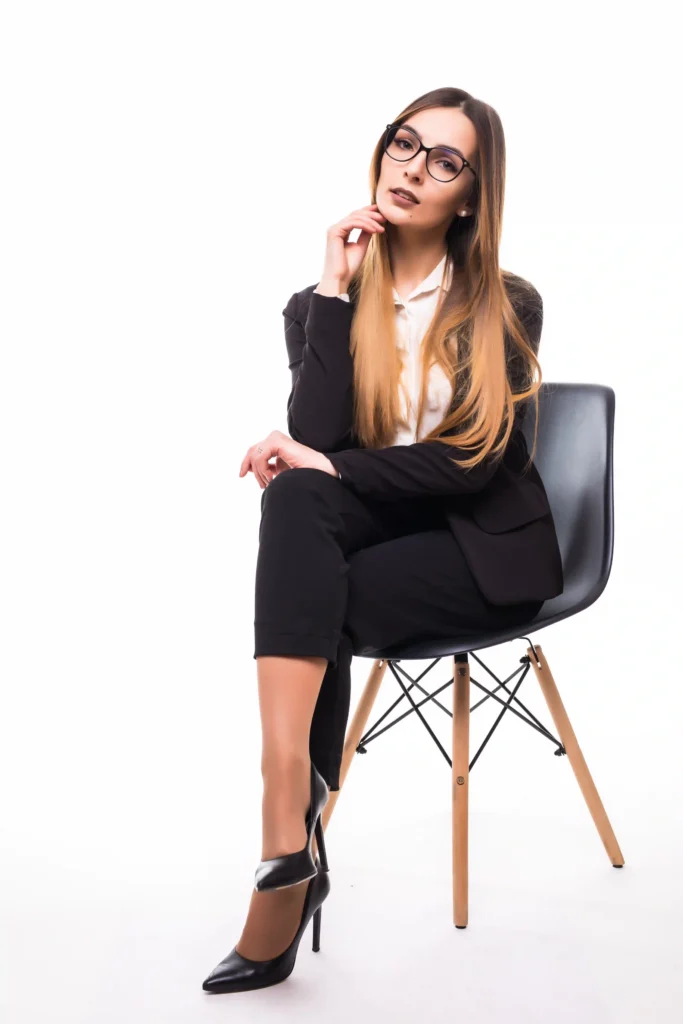 Elegant business women sitting on chair, back is straight, legs poised (not spread or slumped), and hands gently resting in a composed manner.